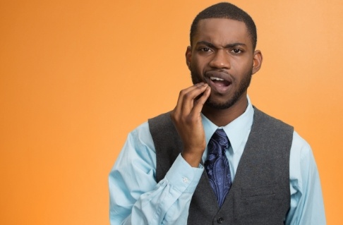 Man in need of emergency dentistry holding jaw in pain