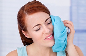 A woman reducing swelling with ice after dental implant surgery