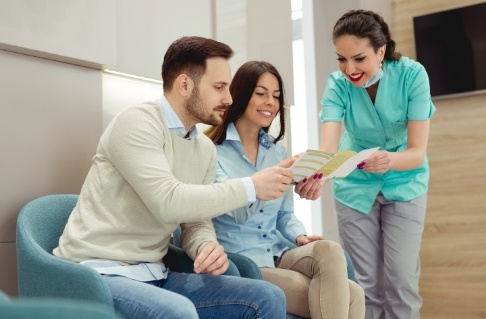 Dental team member and patients discussing dental insurance coverage