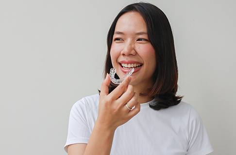 Smiling woman holding clear aligner