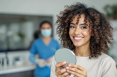 Woman smiling while holding small mirror