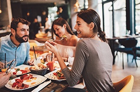 Group of friends smiling while eating in restaurant