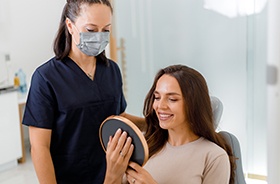 Woman smiling at reflection in handheld mirror