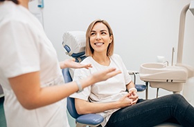 Woman in treatment chair smiling at dentist