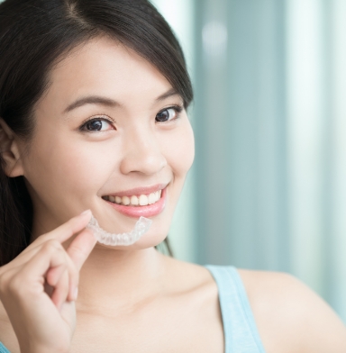 Smiling woman placing a clear aligner tray