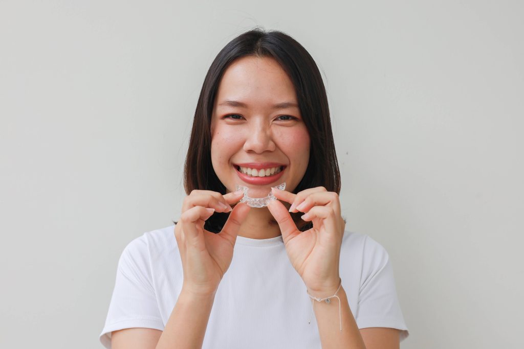 Woman smiling while holding clear aligner